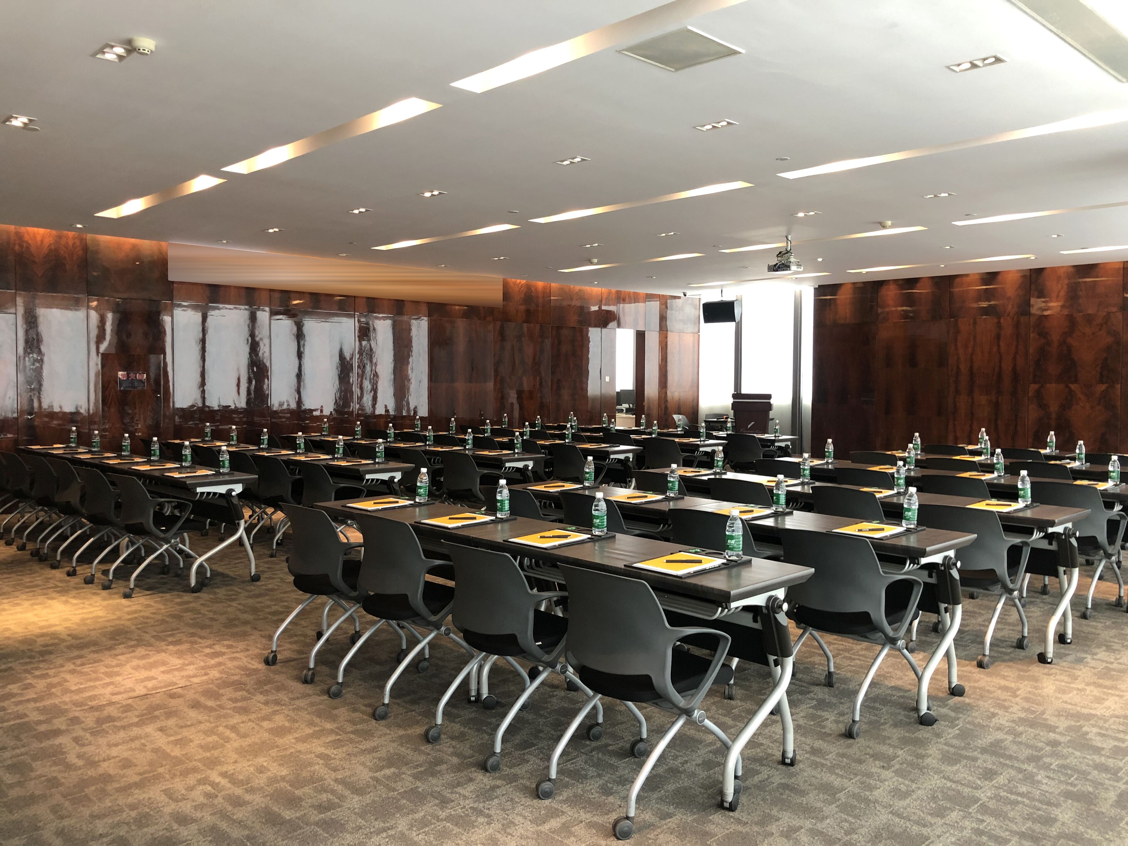A conference room with rows of tables, chairs, and water bottles.