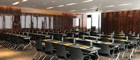 A conference room with rows of tables, chairs, and water bottles.