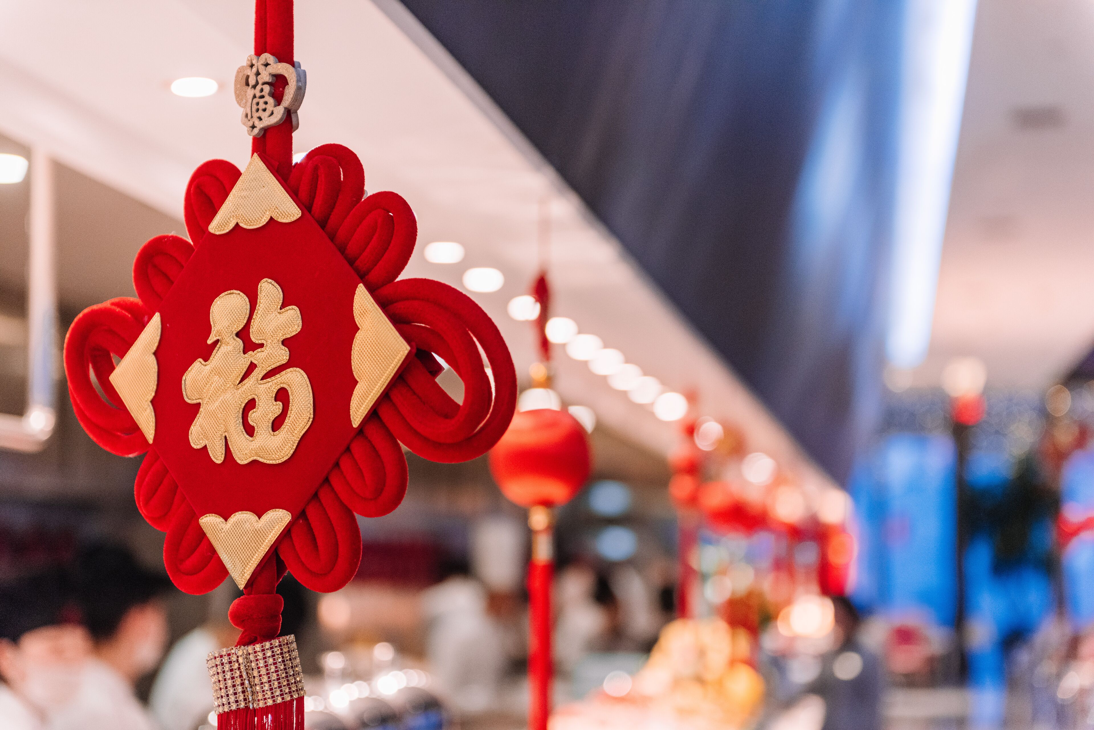 Un élément décoratif rouge, suspendu et orné de broderies dorées, vraisemblablement un ornement de fête.