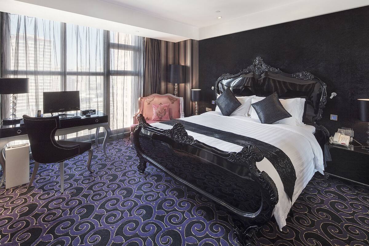 A hotel room with a large bed, a desk with a computer, and a chair.