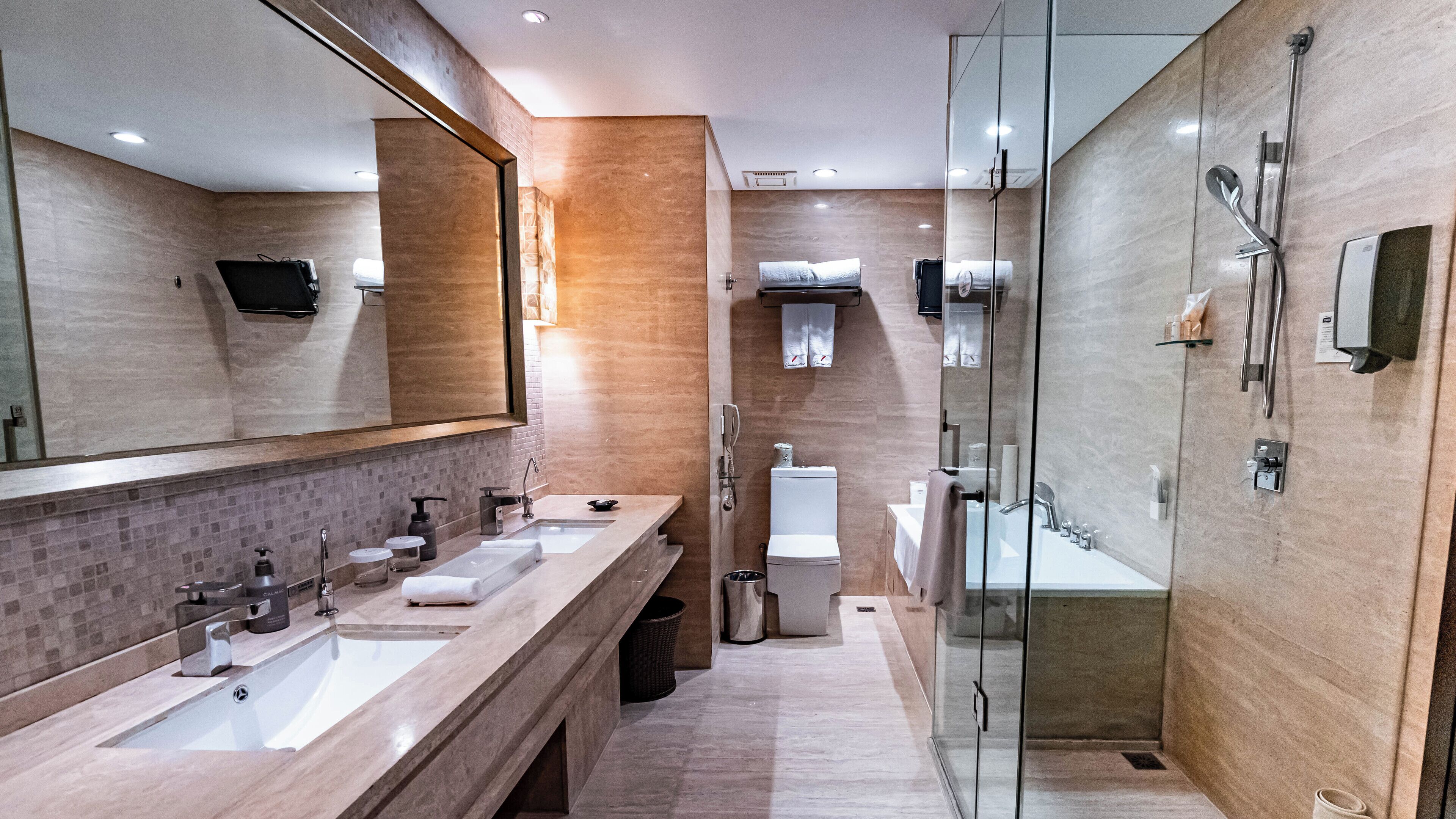 Un baño moderno con un lavamanos espacioso, cabina de ducha de vidrio y un espejo grande.