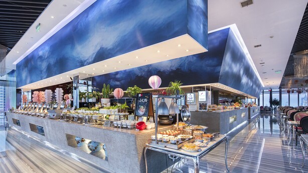 Uma disposição moderna de buffet com diversos alimentos e um mural decorativo no teto.