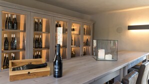Zona de bar con estantes de madera que exhiben botellas, una botella de vino y un candelabro.