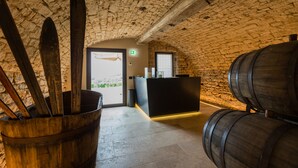 Un interior rústico con paredes de piedra, barriles de madera y esquíes apoyados en la pared.