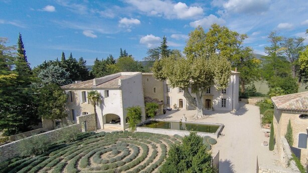 Un edificio de piedra tradicional con un patio, un jardín circular y un pequeño estanque.