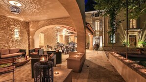 Un patio al aire libre con muros de piedra, arreglos de asientos y un techo decorativo.