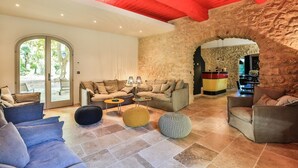 Un amplio salón con una pared de piedra, techo rojo y un gran ventanal que da al exterior.