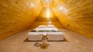 A cozy attic bedroom with a wooden sloped ceiling, a neatly made bed, and a teddy bear on the floor. - Casa Moritz (Brasov)