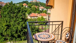 A balcony with a tiled table and chairs, overlooking a residential area with houses and trees. - Casa Moritz (Brasov)