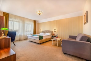 Une chambre d’hôtel comprenant un lit, un bureau, une chaise, un canapé et une petite table.