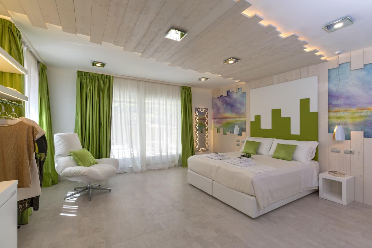A modern bedroom with a bed, a chair, a wardrobe, and a painting on the wall.
