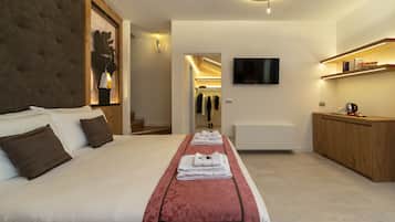 A hotel room with a large bed, a TV mounted on the wall, and a wooden cabinet with books.