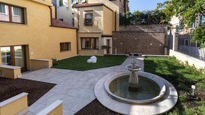 A courtyard with a fountain, steps, and a small garden area. - Ca' de la Fonte | WENICE Deep Culture (Venice)