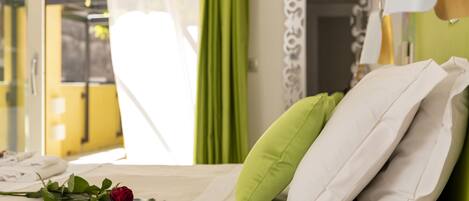 Quarto de hotel com uma cama, cortina verde e parede branca com um padrão decorativo.
