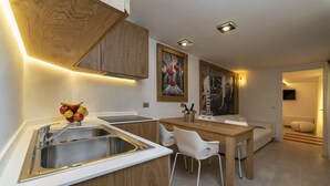 A modern kitchen with a wooden countertop, stainless steel sink, and a dining area with a wooden table and white chairs. - Ca' de la Fonte | WENICE Deep Culture (Venice)