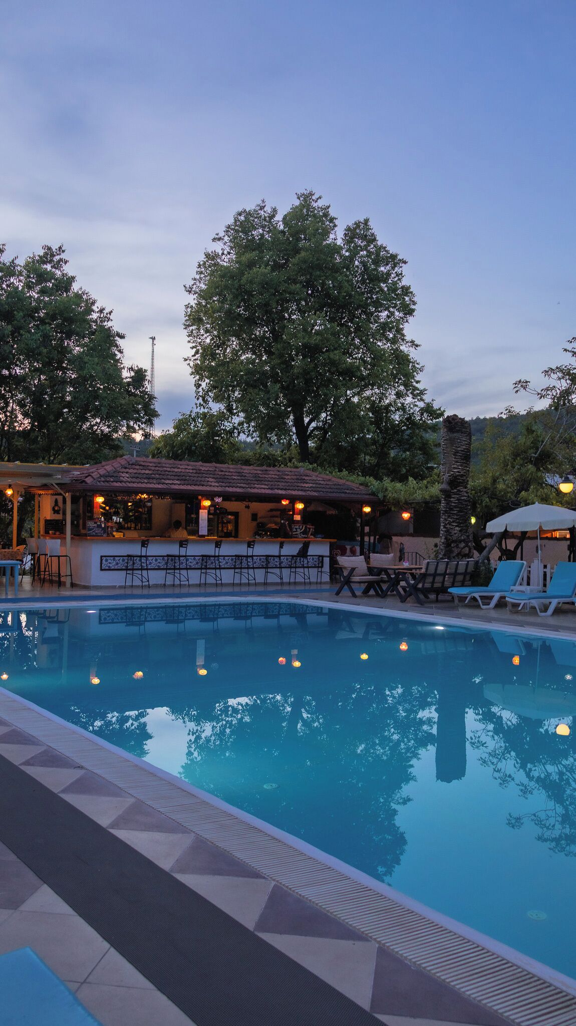 Una piscina al aire libre, sombrillas, sillones reclinables de piscina