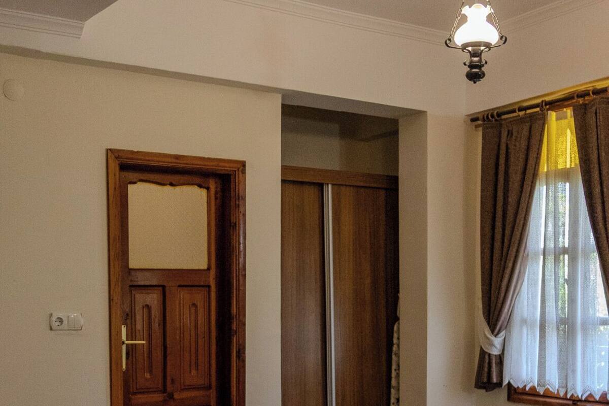 A hotel room with two beds, a sofa, a door, and a ceiling fan.