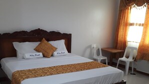 A neatly made bed with a wooden headboard, white bedding, and a patterned throw. There is a small table and two chairs in the corner, and a window with curtains. - Andres Resort (Nabas)