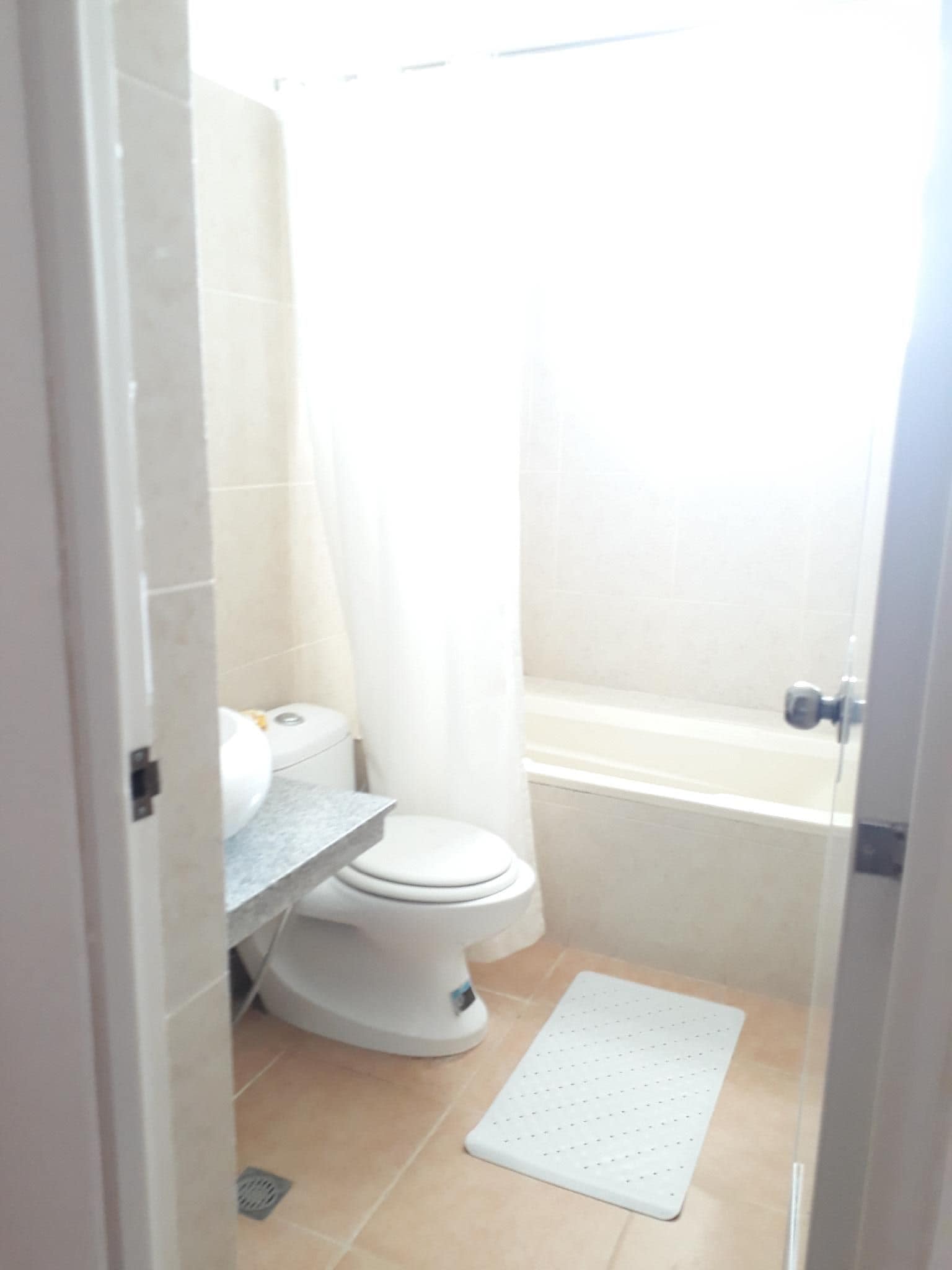 Un baño pequeño y estrecho con inodoro, zona de ducha y lavamanos.