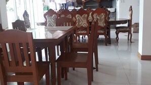 A dining area with a wooden table and chairs, a chandelier, and a kitchen in the background. - Andres Resort (Nabas)
