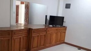 A room with a wooden cabinet, a flat-screen TV, and a mirror. - Andres Resort (Nabas)