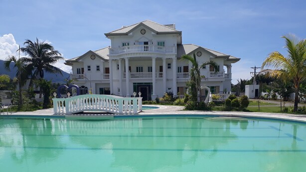 A large, white, multi-story building with a swimming pool in front. - Andres Resort (Nabas)