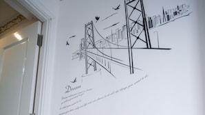 Paredes com um mural de paisagem urbana, dois taburetes de madeira e uma porta.