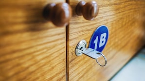 Uma porta de madeira com uma fechadura e uma chave, e uma placa azul com o número "1B".