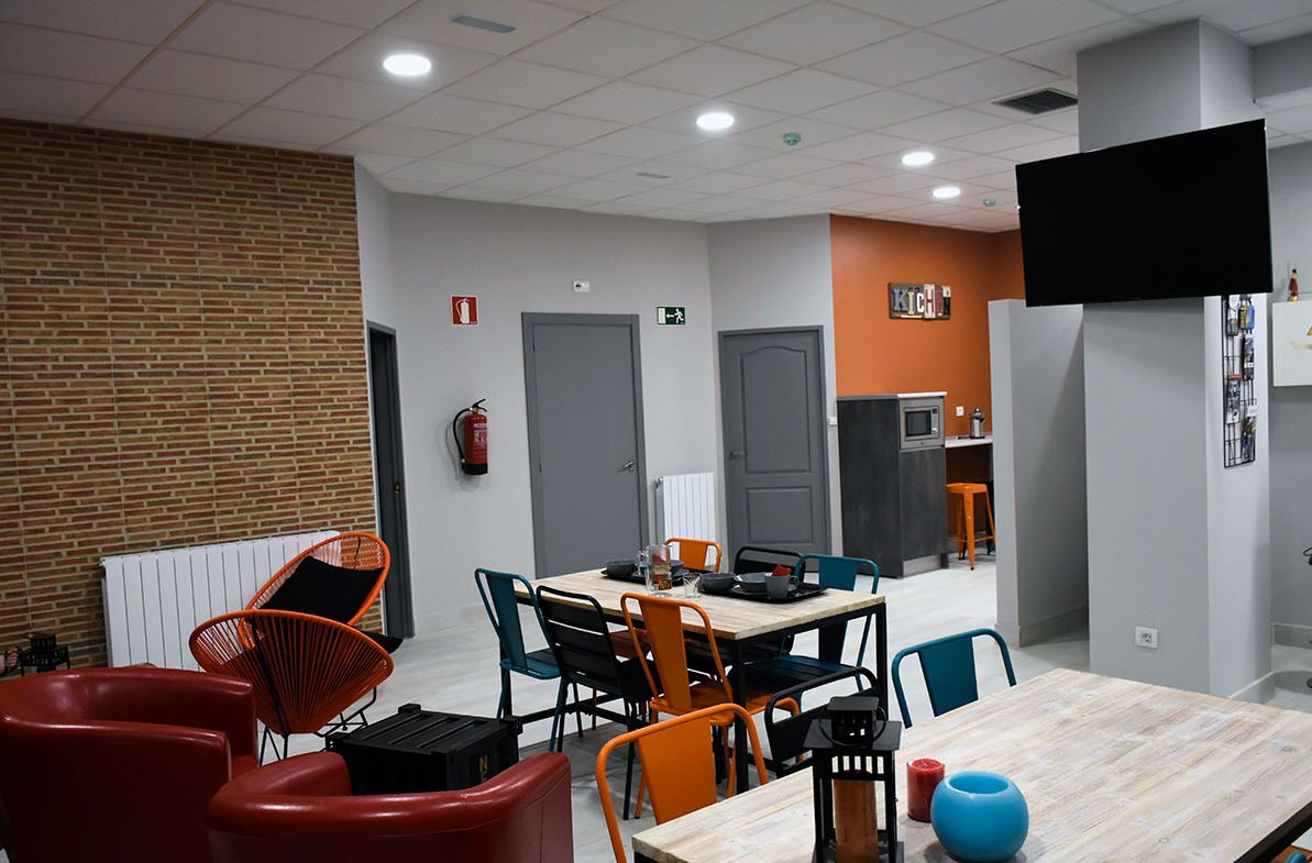 Un comedor moderno con pared de ladrillo, mesa de madera y sillas coloridas.