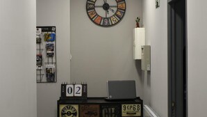 Een gang met een klok, een prikbord en een kast in vintage stijl.