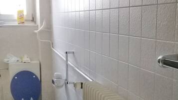 Un baño con inodoro, radiador y ventana.