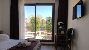 Habitación de hotel con cama, escritorio, silla, televisor y vistas al exterior.