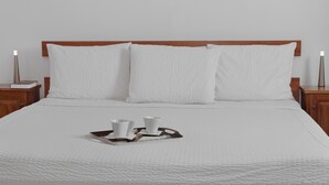 A neatly made bed with white linens and pillows, a tray with two cups and a saucer, and wooden nightstands with lamps. - SwissGha Homes Christian Retreat and Hospitality Center (Tema)
