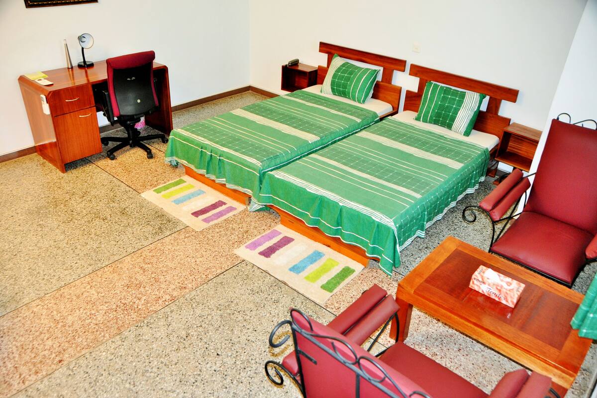 Une chambre avec deux lits, un bureau, une chaise et une petite table.