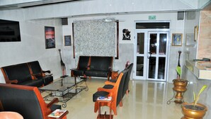 A lobby with a reception desk, a glass coffee table, leather sofas, and a patterned curtain. - SwissGha Homes Christian Retreat and Hospitality Center (Tema)