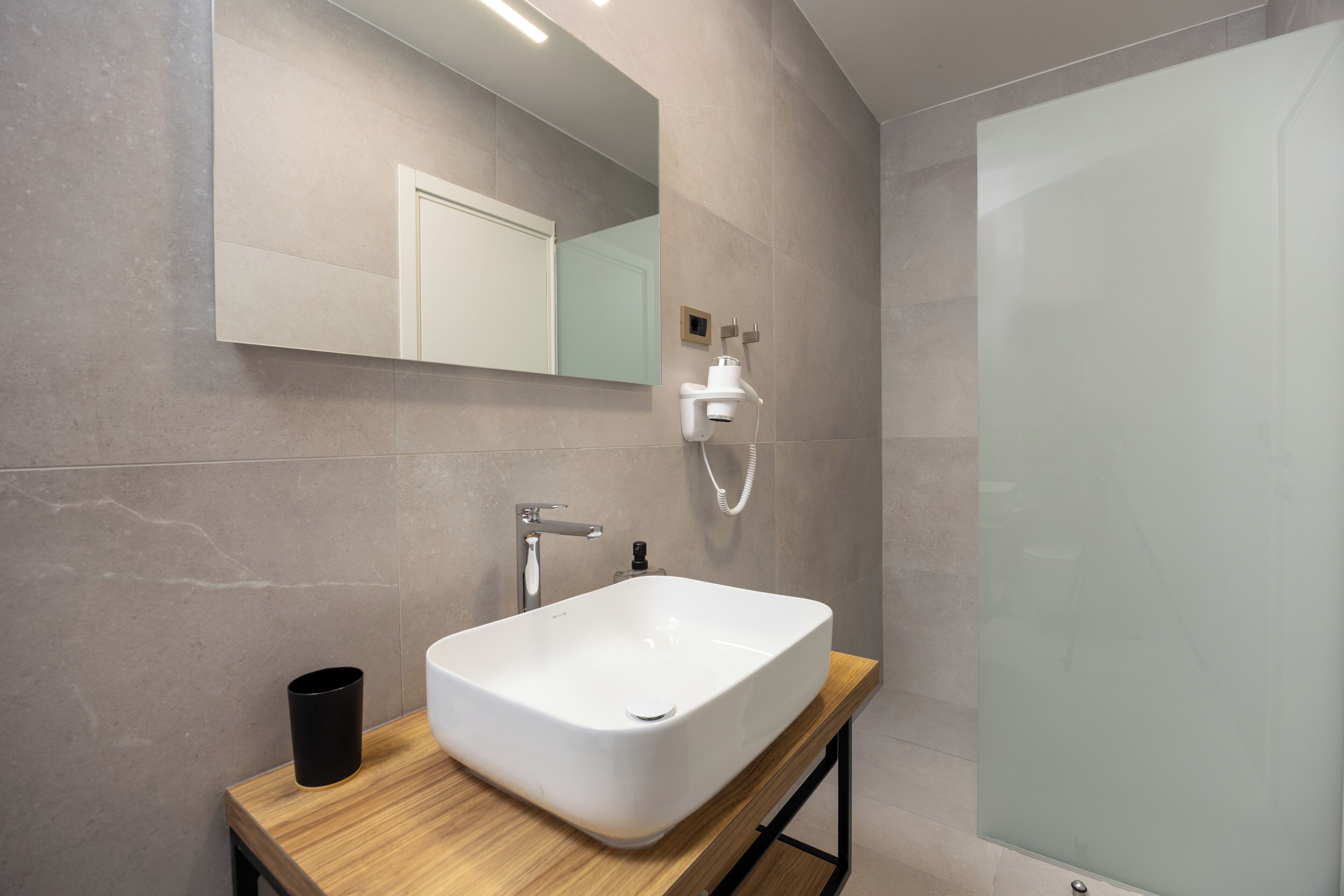 A modern bathroom with a large rectangular sink, a mirror, and a shower.