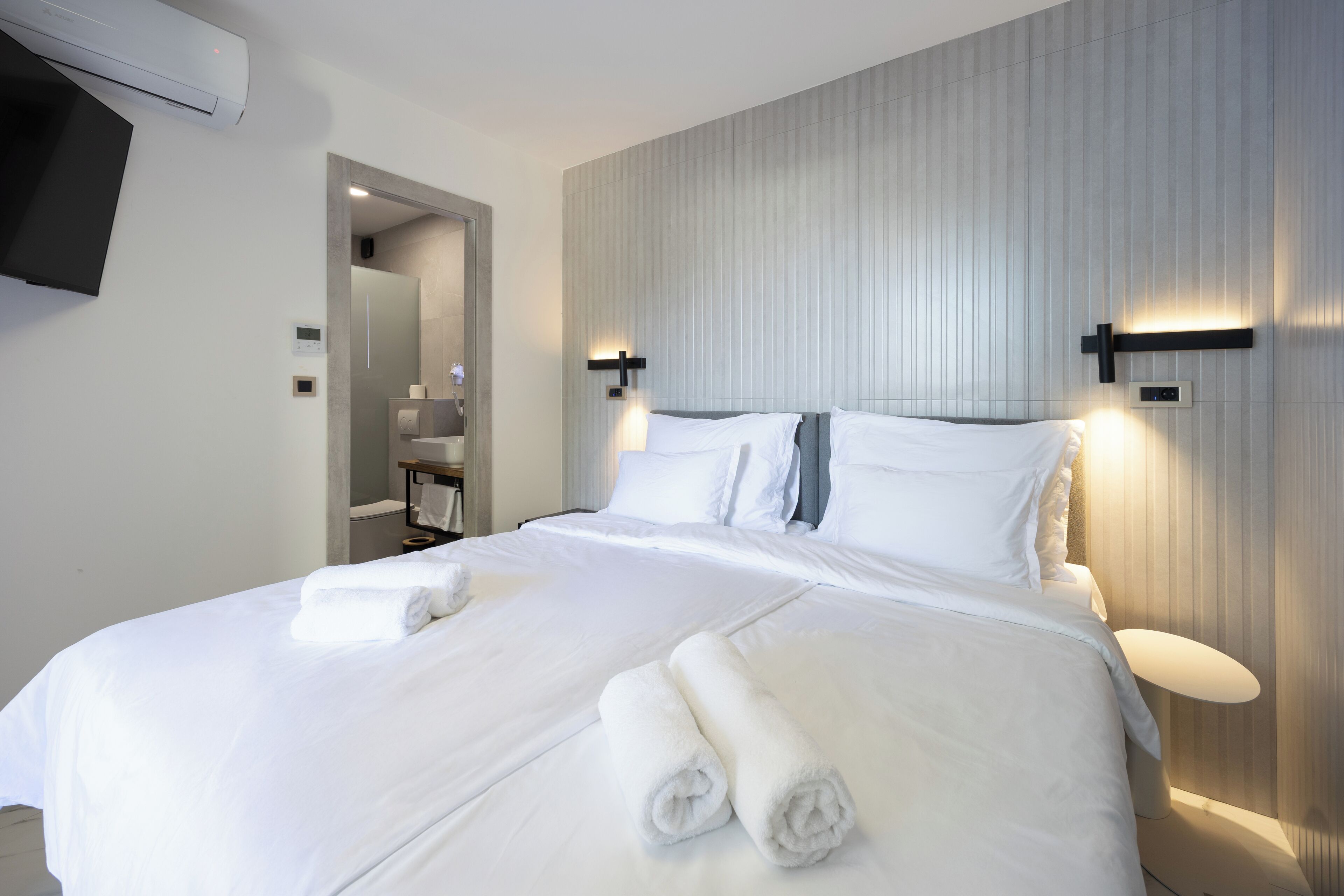 Una habitación de hotel con una cama grande, dos lámparas de pared y un televisor de pantalla plana.