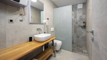 Une salle de bain moderne avec un meuble-lavabo en bois, un lavabo blanc, des toilettes et un espace douche agrémenté de carreaux à motifs.