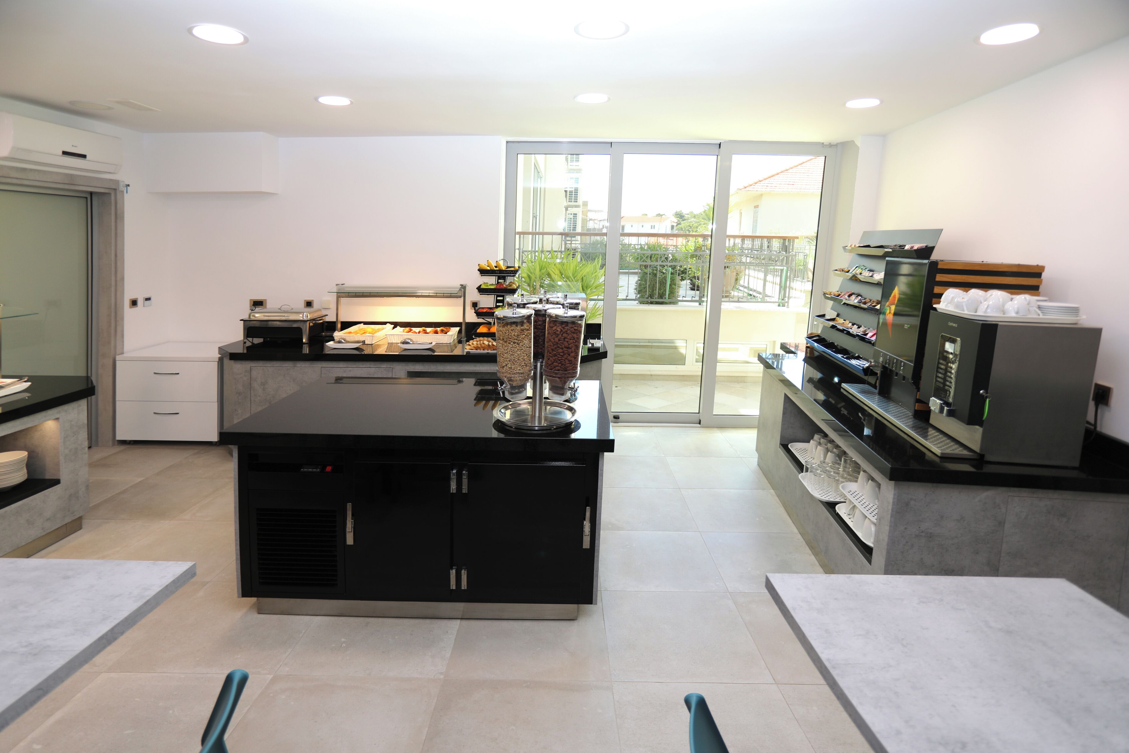 A modern kitchen with a central island, built-in appliances, and a glass door leading to a balcony.