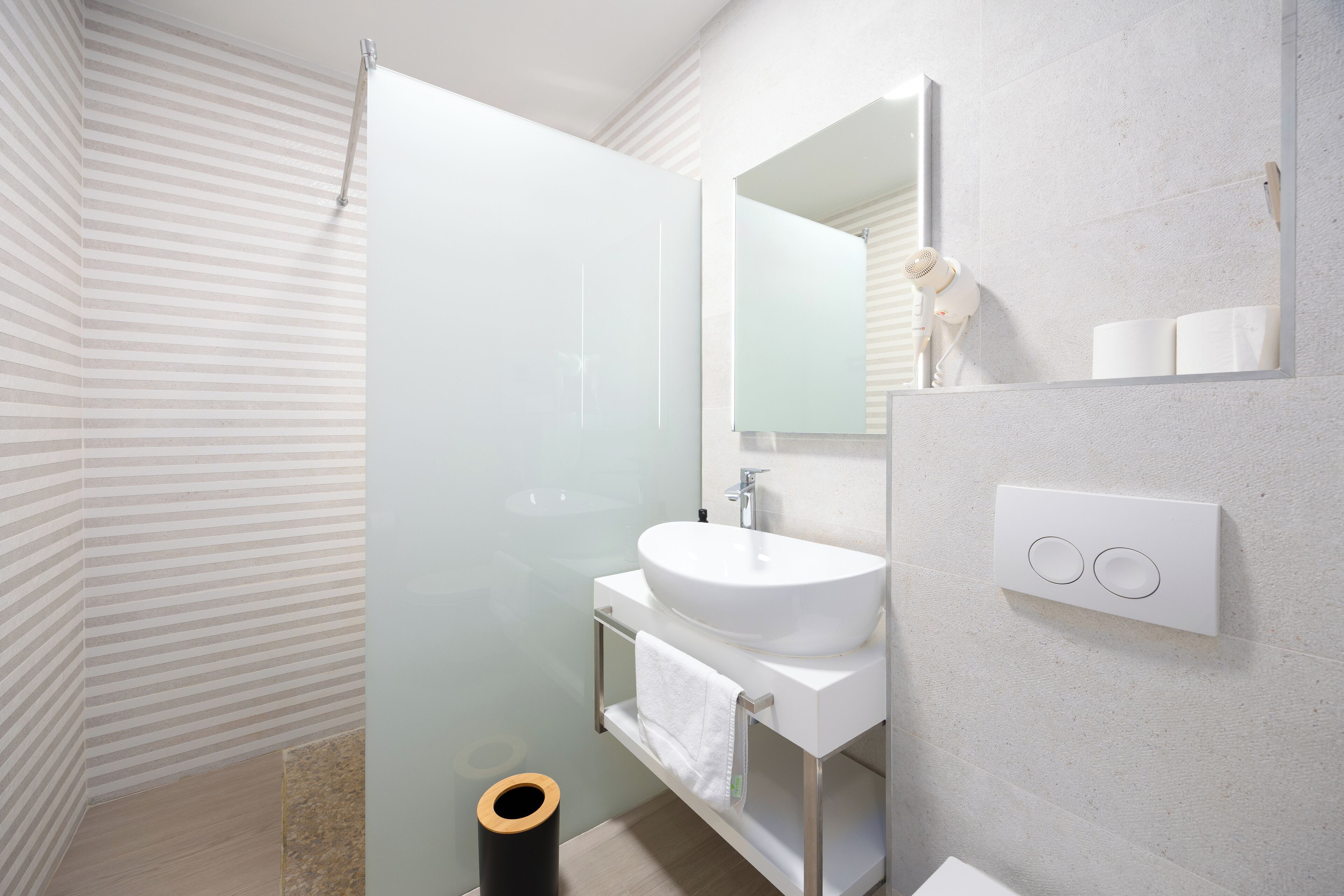 A modern bathroom with a glass shower enclosure, a white sink, and a large mirror.