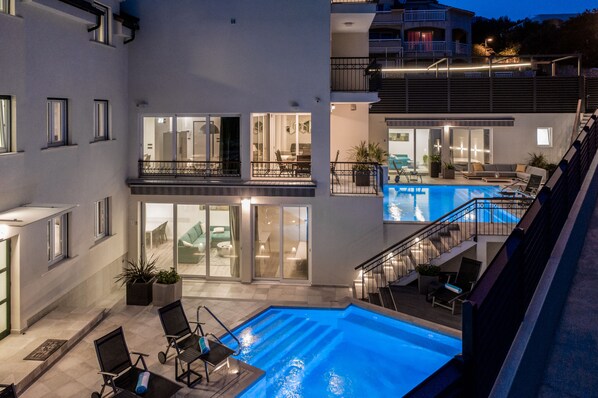 A multi-level residential building with a swimming pool, outdoor seating, and a balcony with a railing. - Hotel Teranea (Hvar)