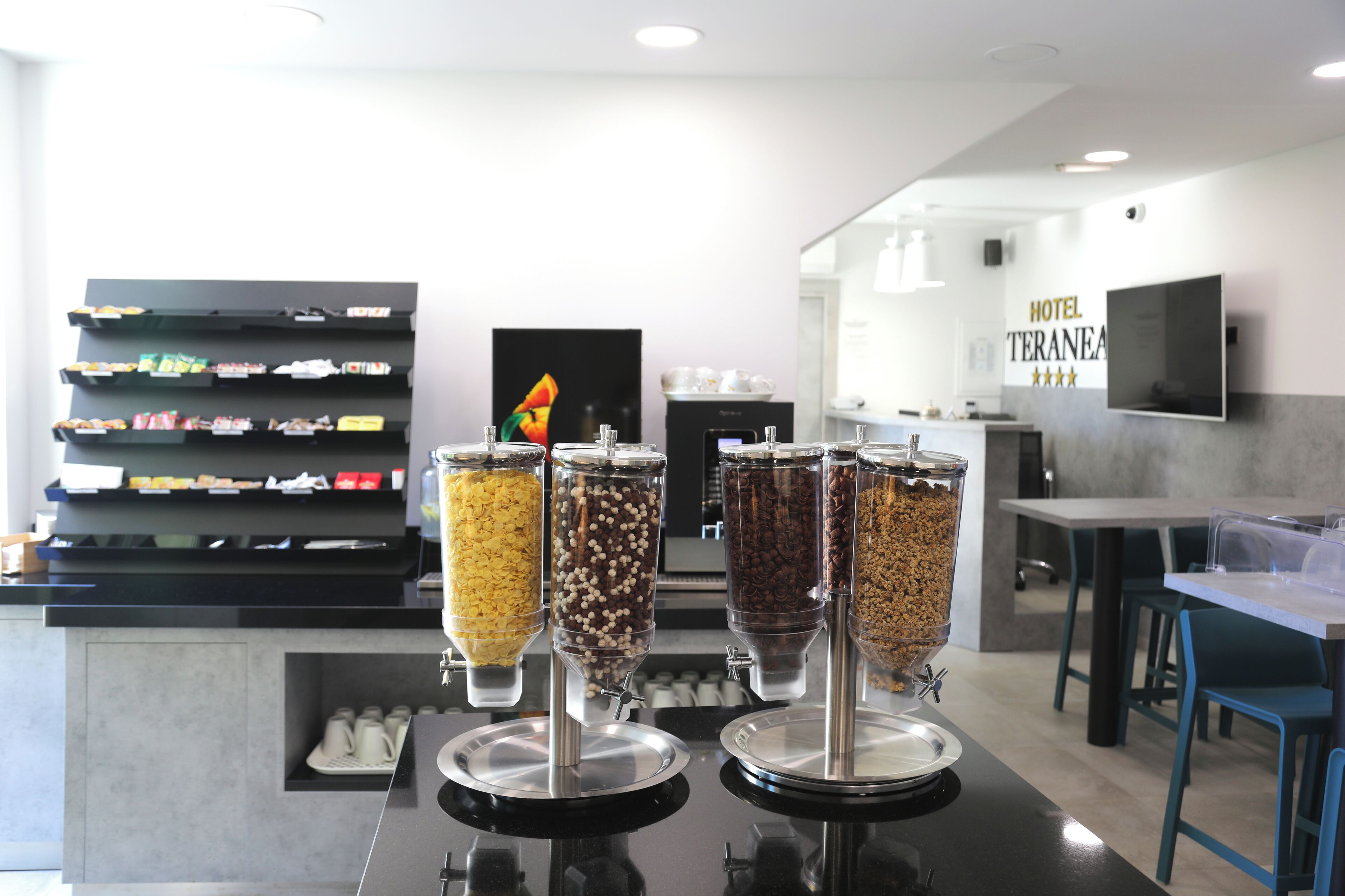 A hotel lobby with a self-serve coffee station featuring various coffee beans and a display of snacks.