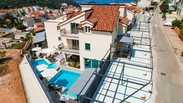 Um edifício moderno com piscina no terraço, várias varandas e vista para o bairro ao redor.
