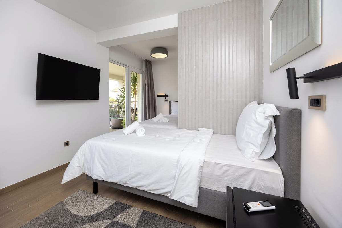 Habitación de hotel moderna con cama, televisor de pantalla plana, mesita de noche y vistas al exterior.