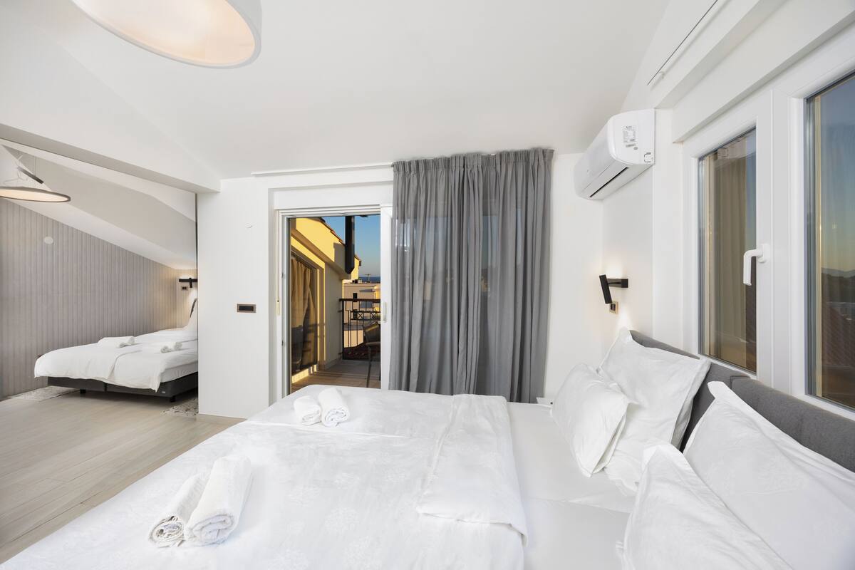 Habitación de hotel moderna con una cama grande, una zona de estar separada y vistas al exterior.