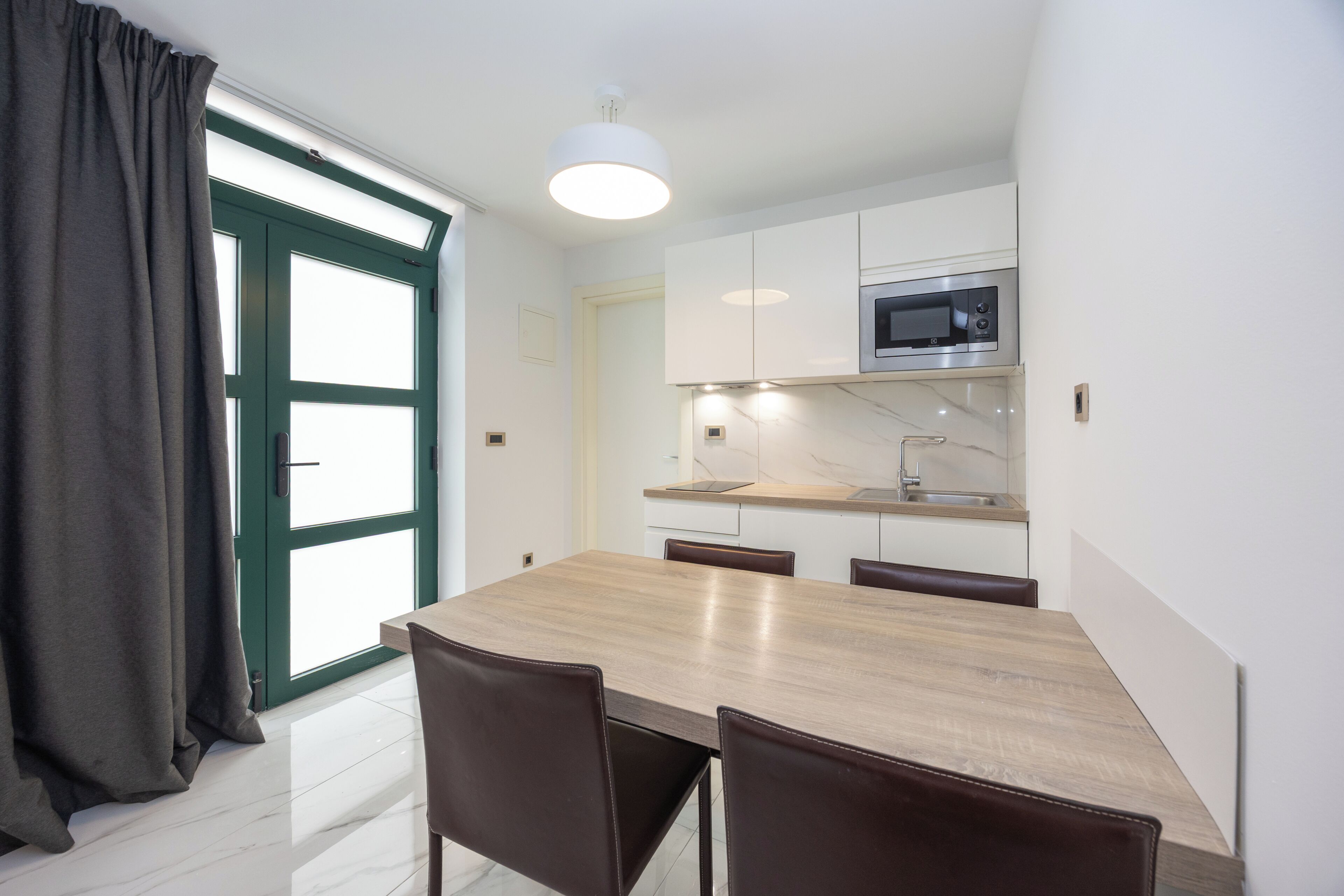 Una cocina moderna con microondas, armarios y una mesa de comedor con sillas.