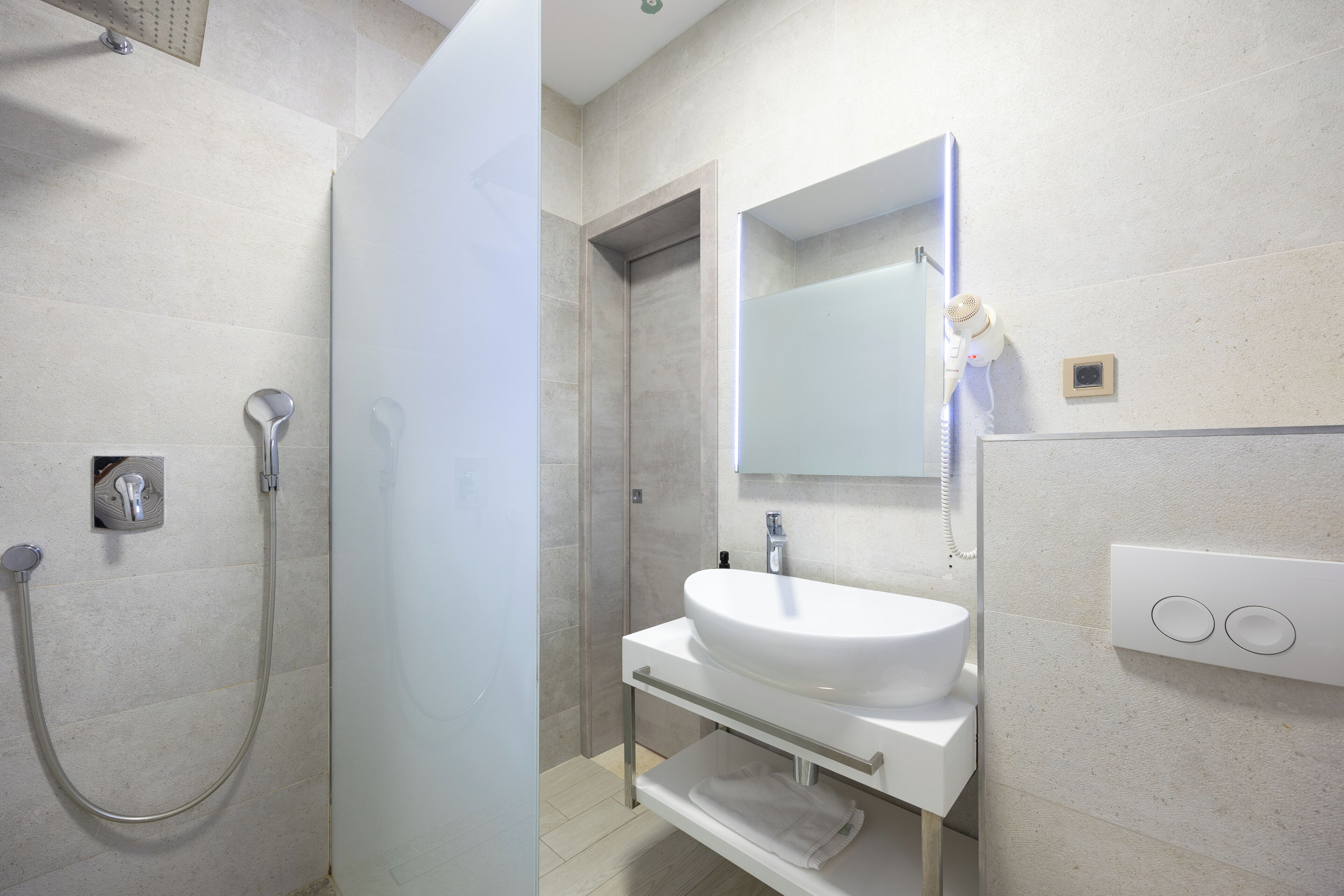 A modern bathroom with a glass-enclosed shower, a white sink, and a mirror above it.