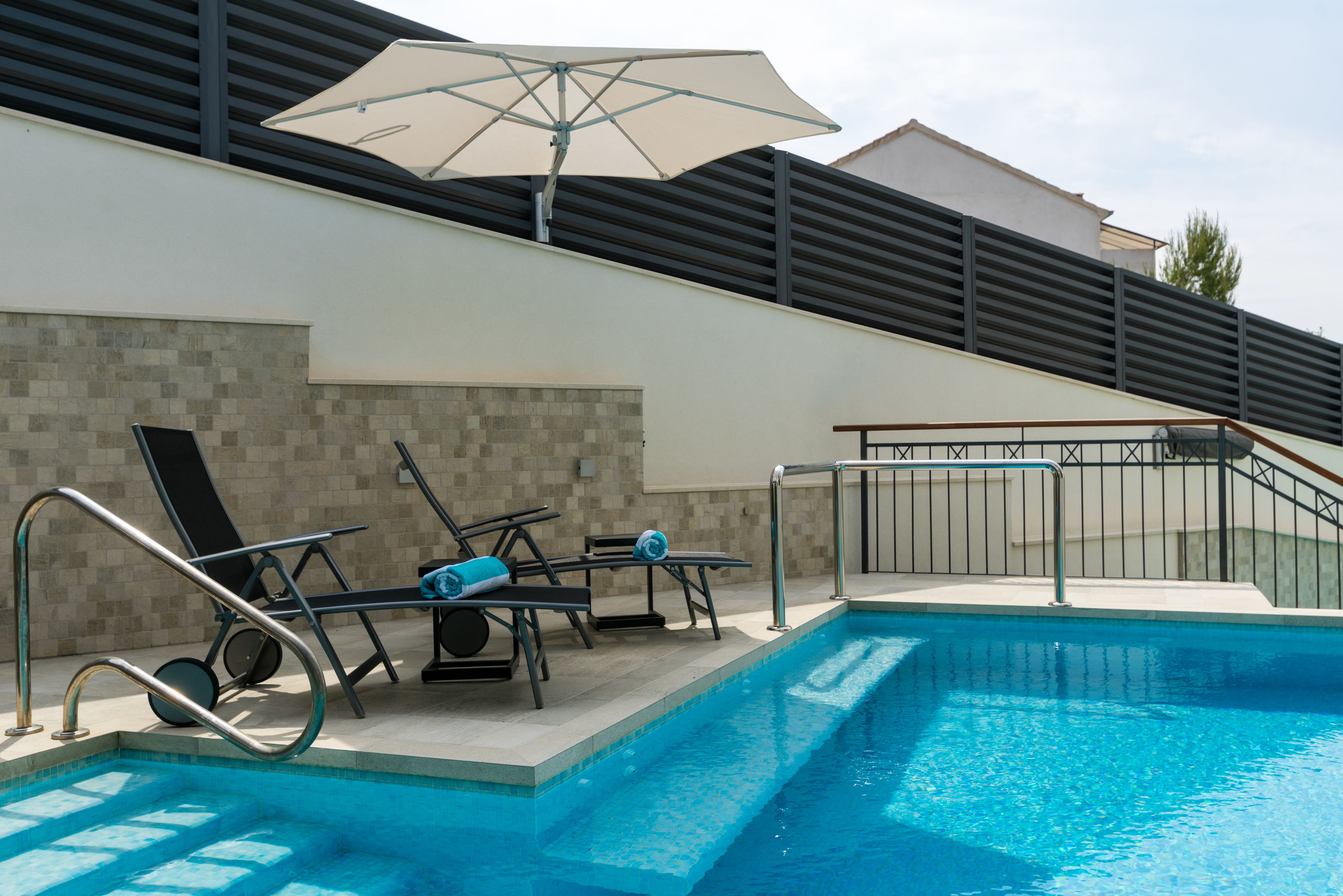 Une piscine avec des chaises longues et un parasol.