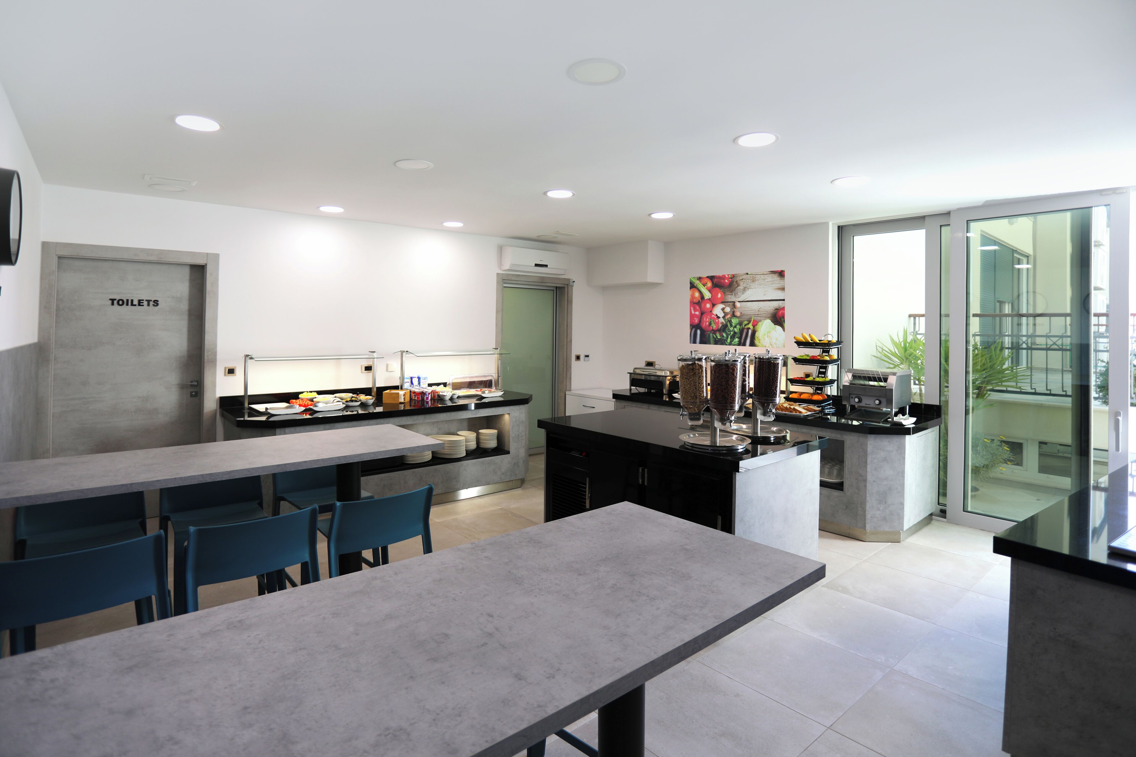 A modern kitchen with a dining area, a refrigerator, and a coffee machine.