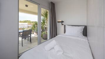 Una habitación de hotel con una cama, vistas al balcón y un comedor con mesa y sillas.